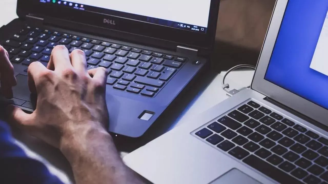 A person typing on one laptop