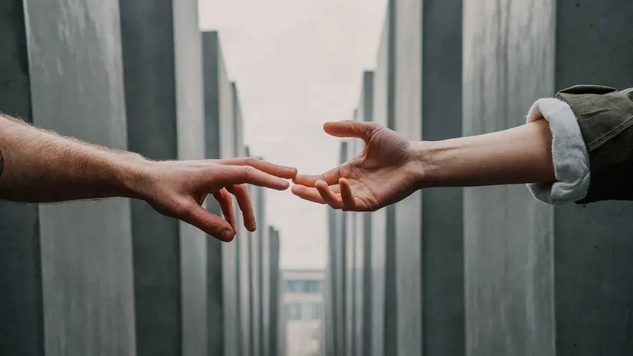 Two people holding hands towards each other 
