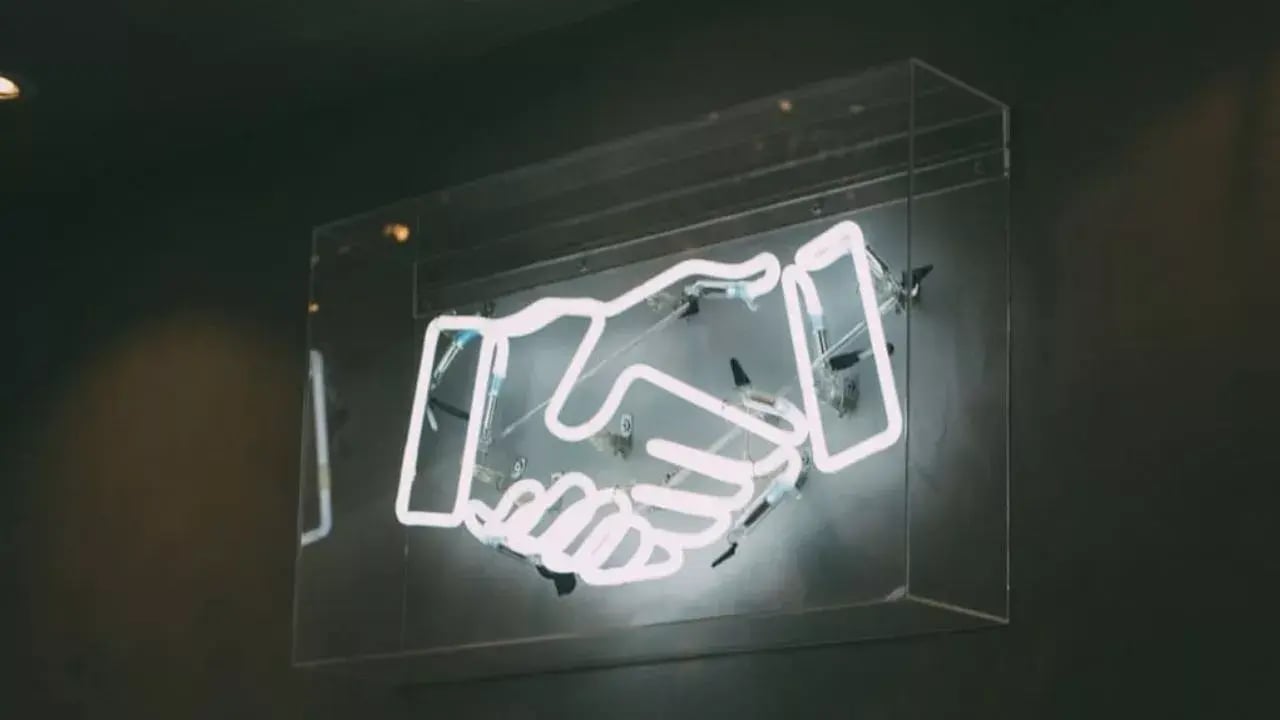 Neon sign of two hands shaking hands
