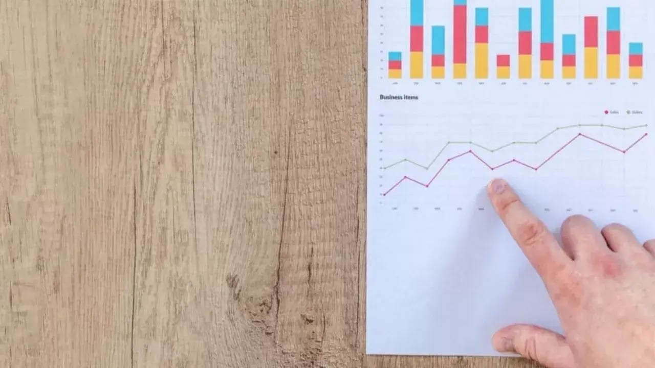 A hand points to a graph on a piece of paper lying on the table