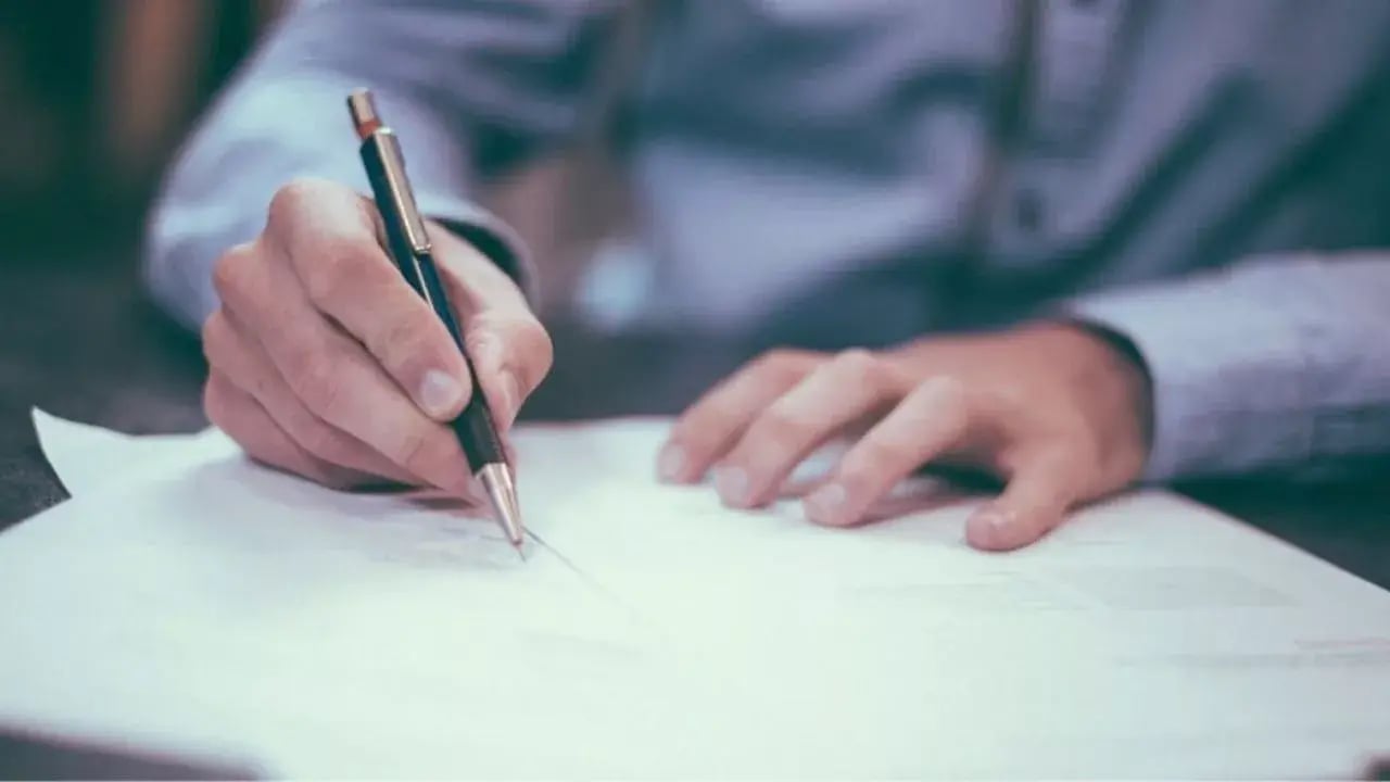 The person writes on a piece of papper with a pen