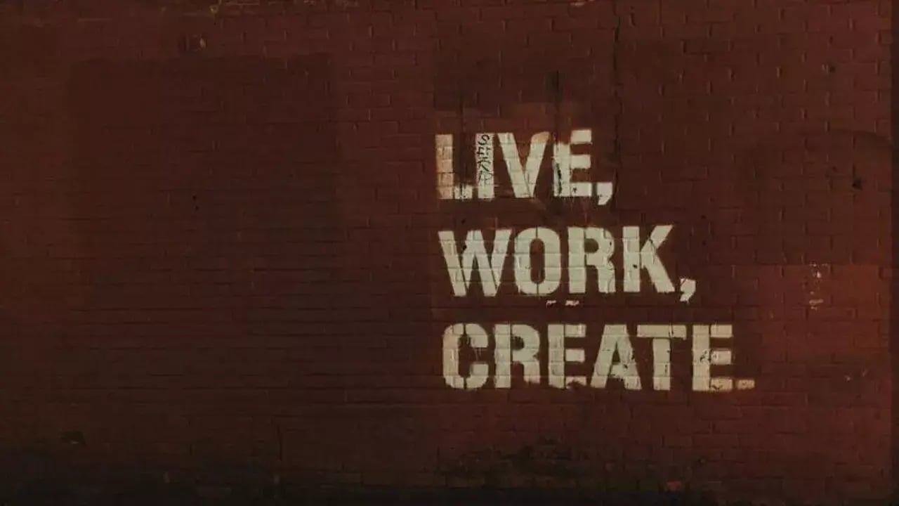 A brick wall with the phrase live work create painted in bold