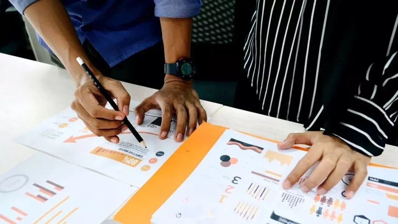 Two individuals working at the table covered with documents