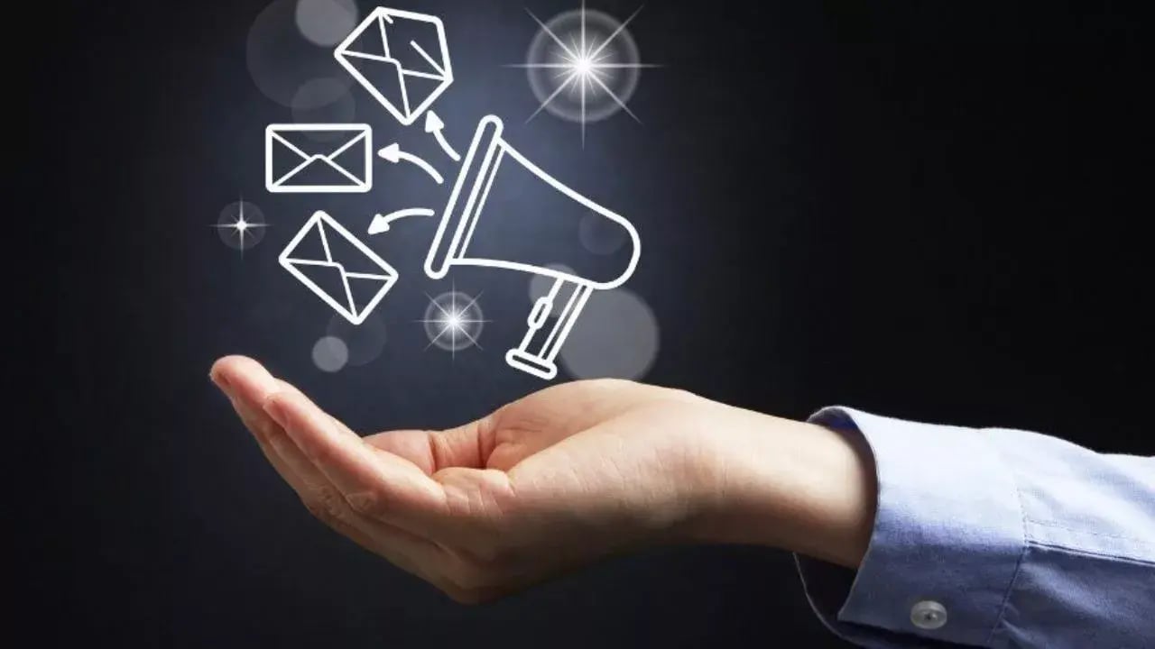 a hand holding outwards, with a graphic representation of a megaphone and envelopes emerging from it