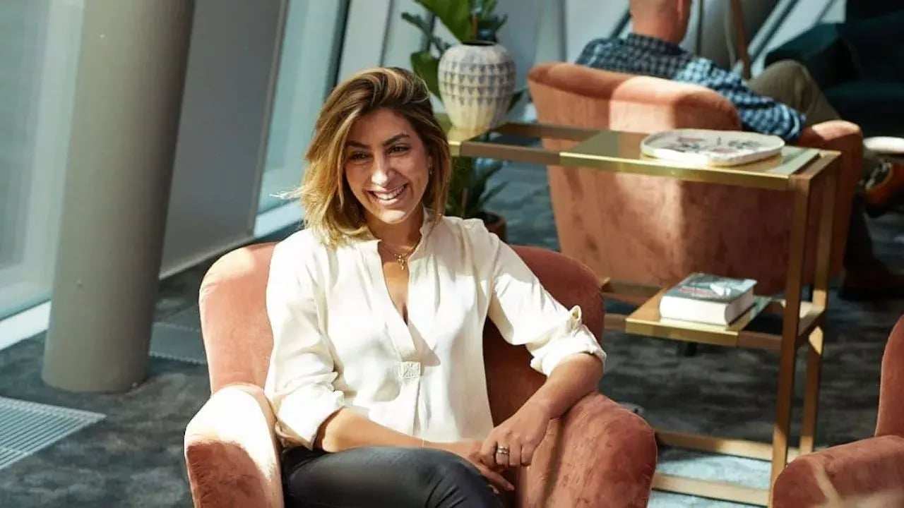 A woman sitting comfortably in a stylish, modern chair, smiling warmly at the camera.