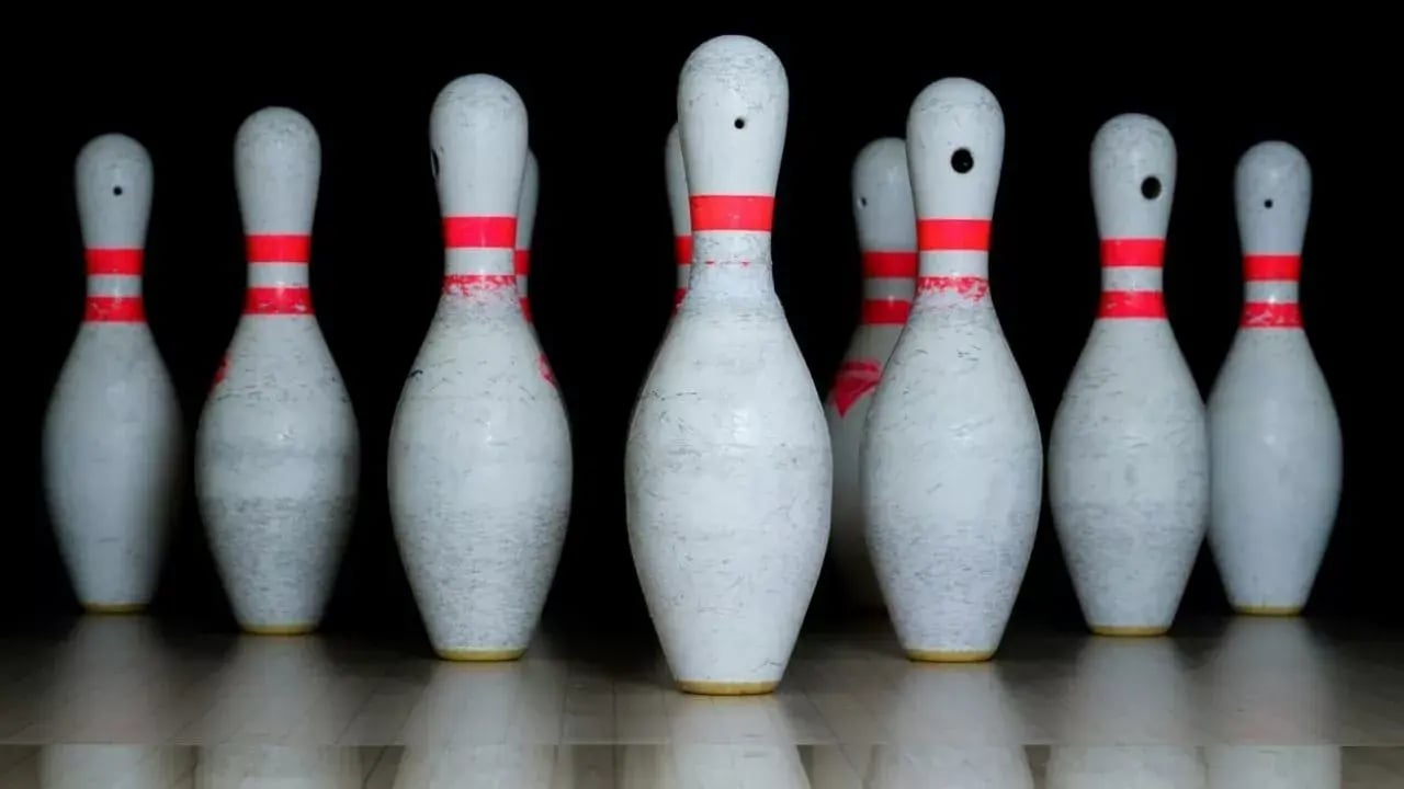 a group of bowling pins arranged in a triangular formation, predominantly white with red stripes