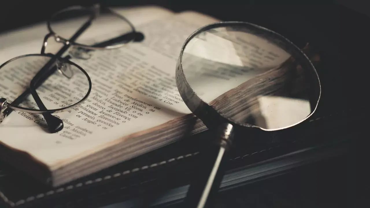 The image shows a magnifying glass resting on an open book.