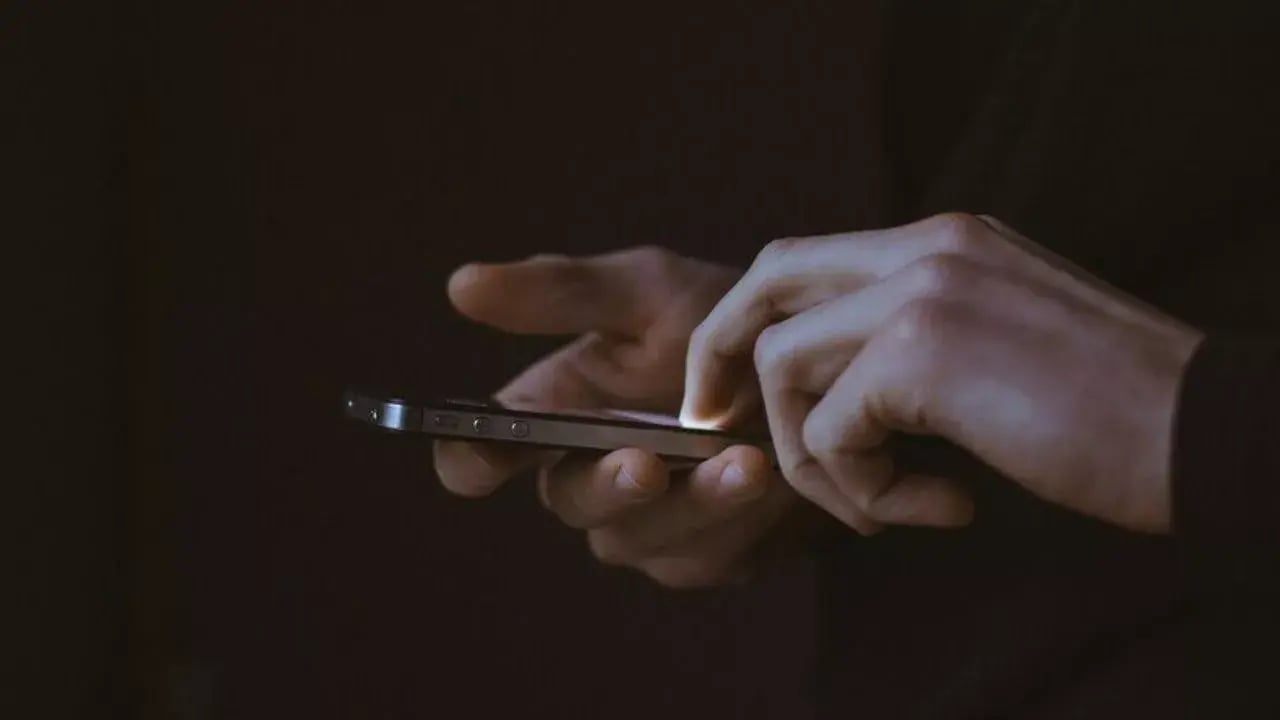 a close-up of a person's hands holding a smartphone, with fingers poised to interact with the screen