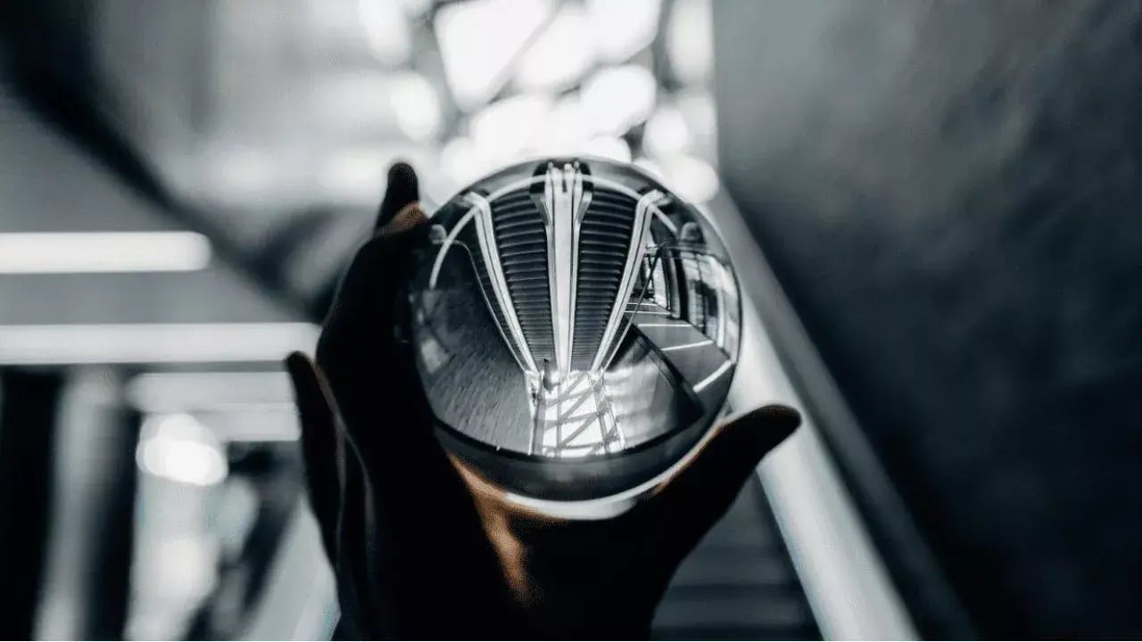a person holding a crystal ball that reflects a modern architectural space, including stairs and structural lines
