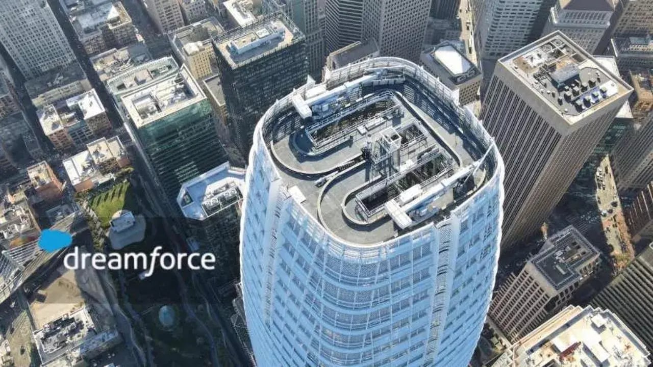 A bird's-eye view of a modern skyscraper in an urban setting, surrounded by various buildings.