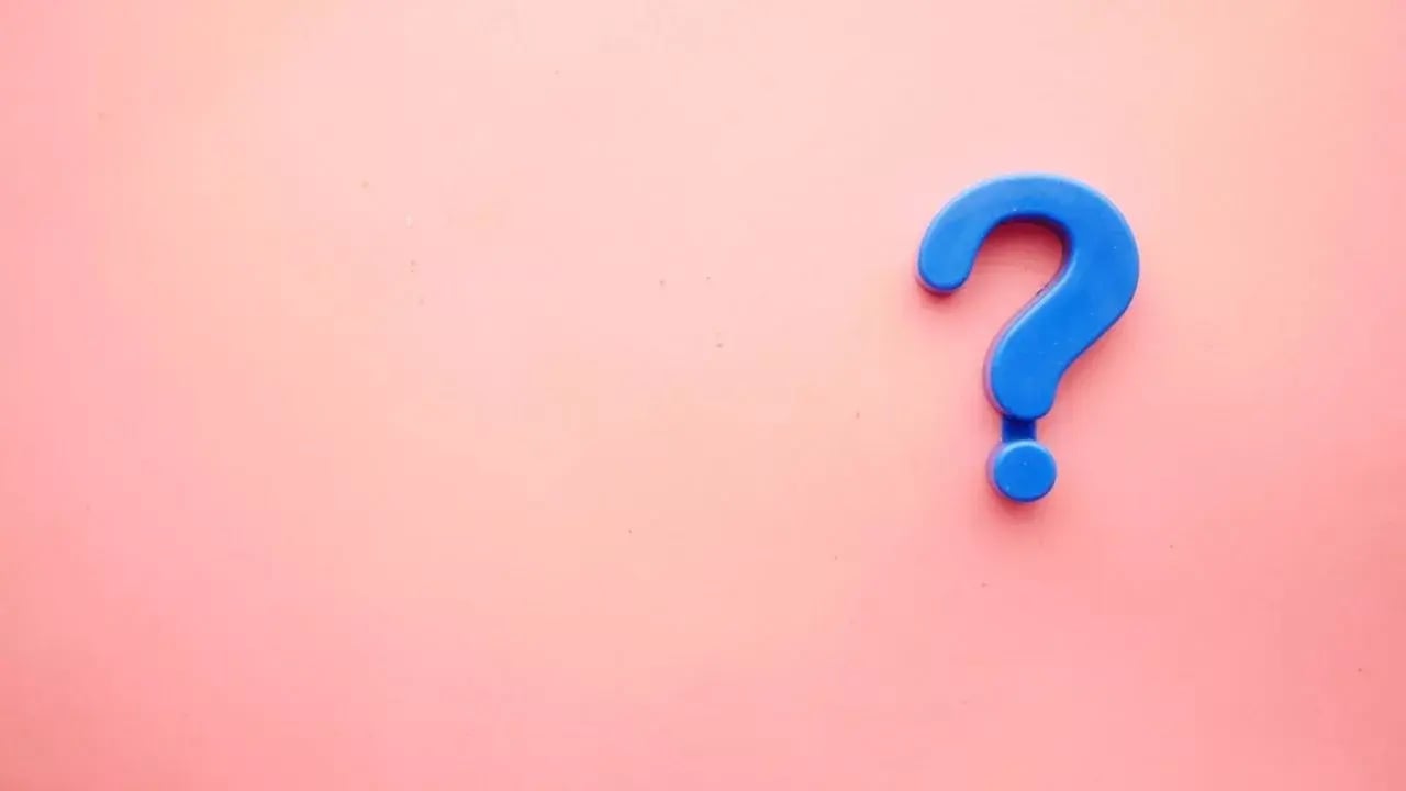 A blue question mark symbol on a soft pink background