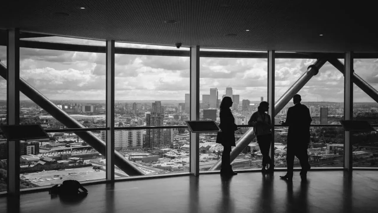 A group off three people standing and look out from the window