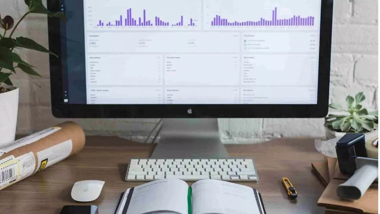 a workspace featuring a computer monitor displaying data visualizations, including bar graphs and statistics