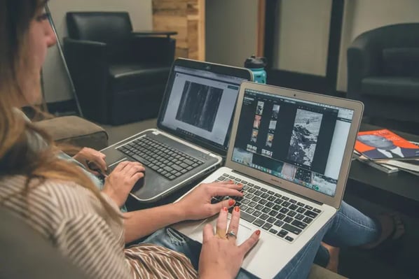 Two individuals working on laptop computers in a casual workspace.