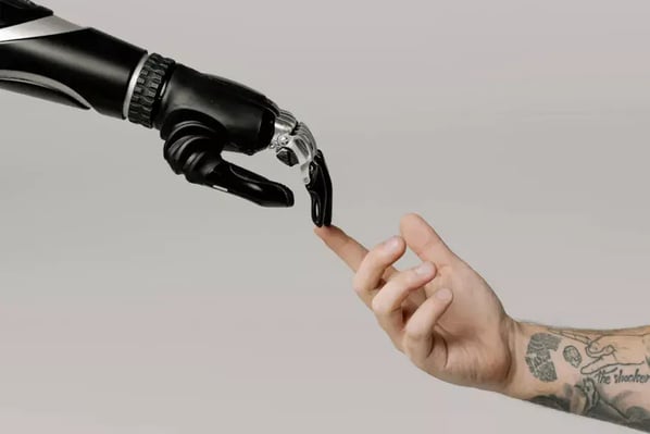 A robotic arm with human-like fingers extending towards a human hand, which is positioned to interact with the robot's fingers.