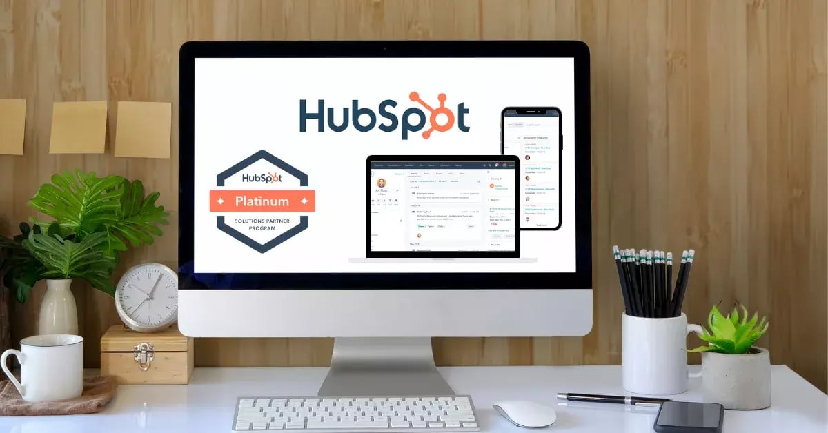 The image shows a desktop computer with the HubSpot logo displayed prominently on the screen.